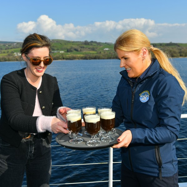 Two women on a boat holding glasses of Irish coffee.